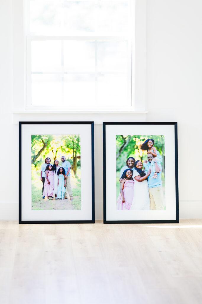 Two large black-framed family portraits leaning against a white wall, illustrating how to display printed photos from a professional family session.