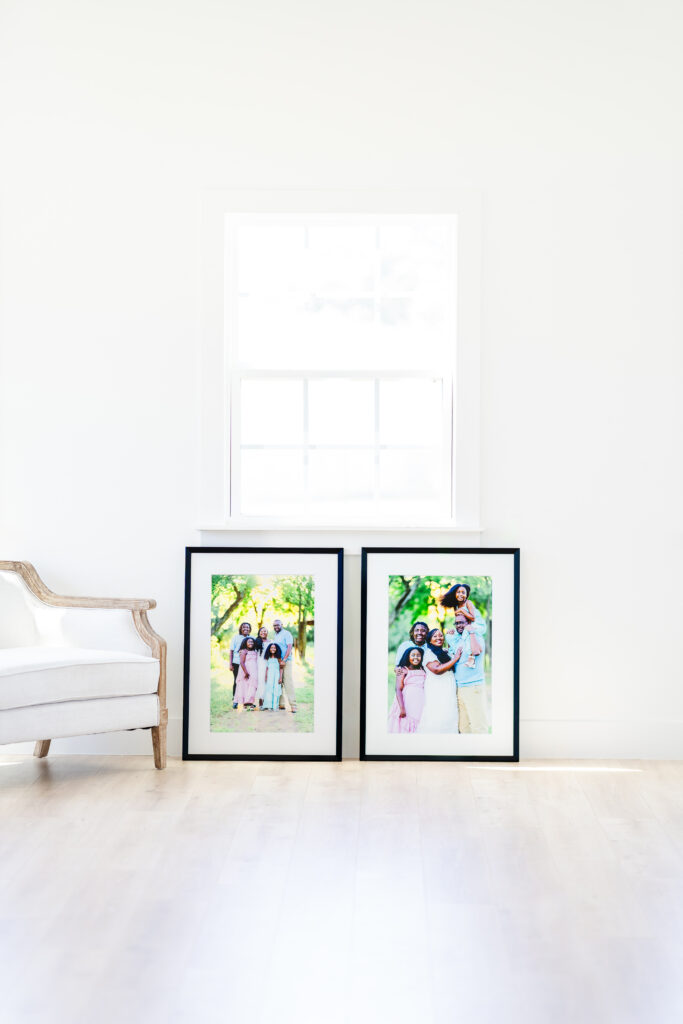 Two large black-framed family portraits leaning against a white wall, illustrating how to display printed photos from a professional family session.