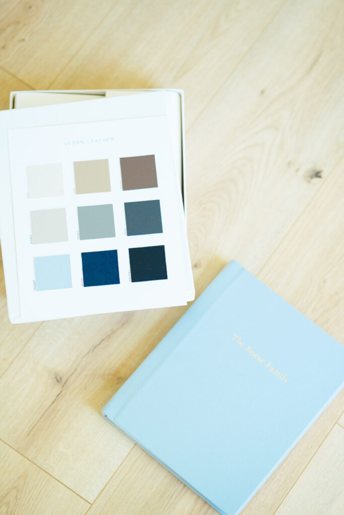 Flat lay of heirloom family photo album in light blue vegan leather with a swatch book of cover color options, showcasing custom print products for natural light family photography in Dallas.