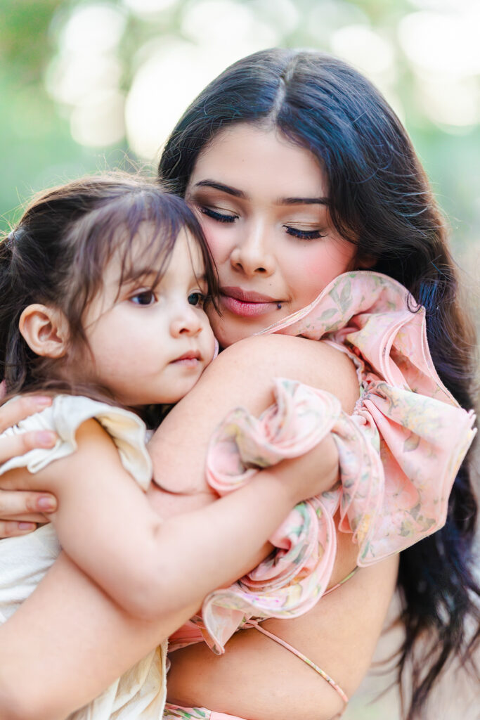 BMother holding her young daughter close during a quiet outdoor moment