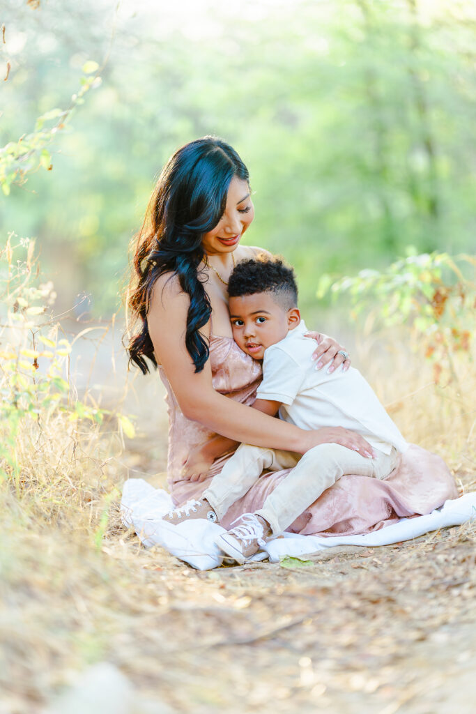 Mother sitting outdoors holding her young son close during a quiet moment together