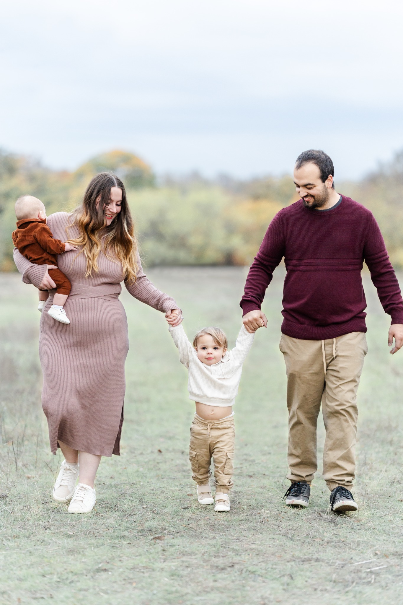 Family walking through the muted fall landscape at Arbor Hills in Plano in coordinated burgundy, mauve, cream and tan outfits