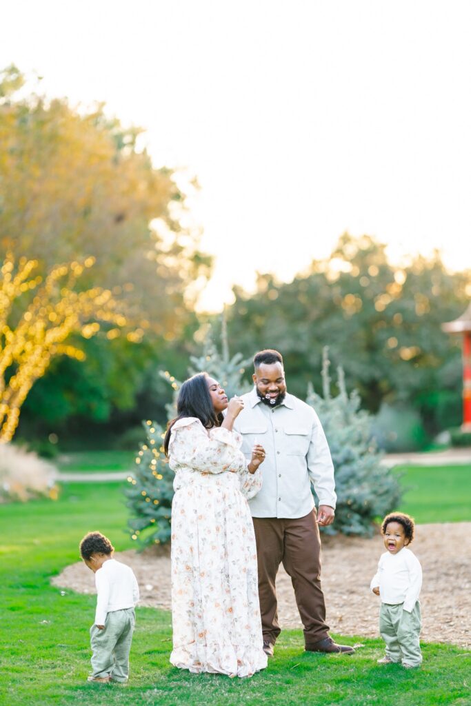 Parents playing with their twin toddlers during a golden-hour family session at the Dallas Arboretum.