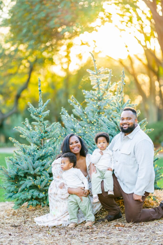 Family of four photographed among illuminated Christmas trees at the Dallas Arboretum.